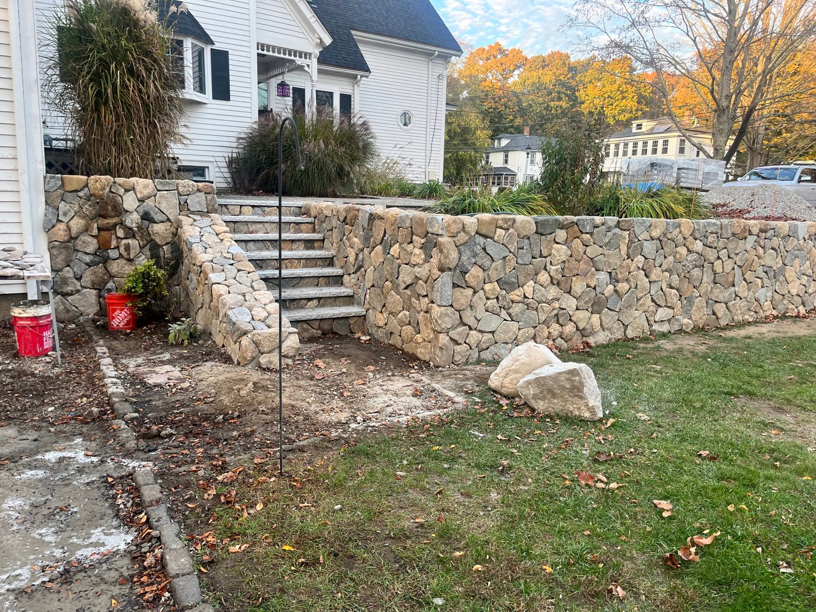 Retainer wall using stone veneer materials in the front yard. There is grass in the front as well as a house in the back